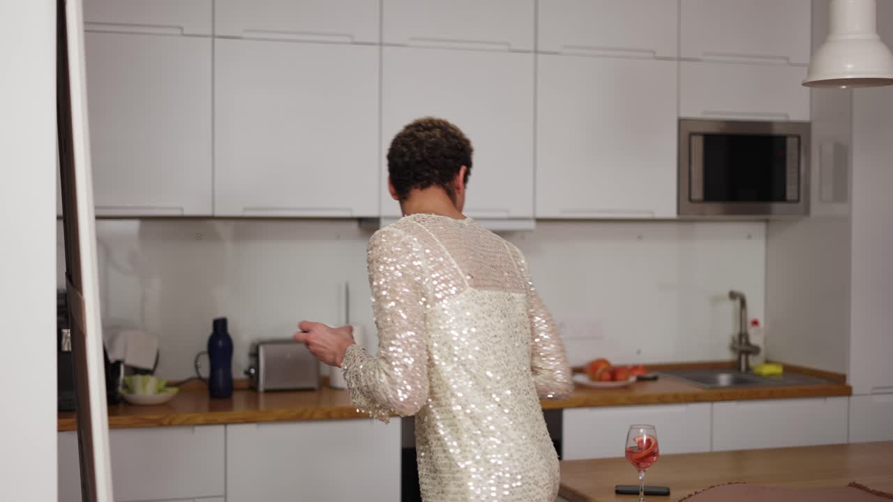 un hombre en un vestido de pie frente al espejo, haciendo maquillaje