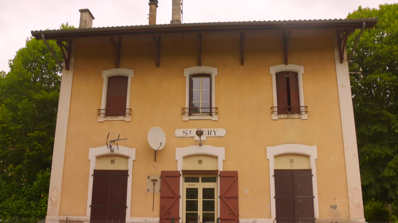 Shot of a former railway station with overgrowing nature in Saint-Géry, France on a cloudy day. 4k
