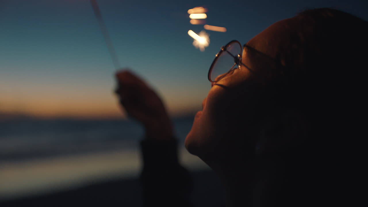 retrato chica de raza mixta sosteniendo bengala en la playa al atardecer celebrando la víspera de año nuevo joven disfrutando de la celebración del día de la independencia el 4 de julio