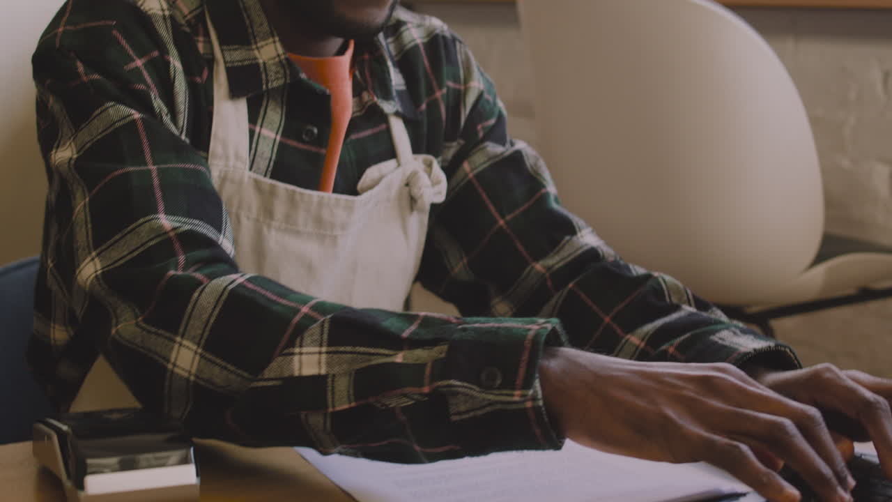 dueño de la cafetería sentado en la mesa y calculando la factura financiera en la computadora portátil 2