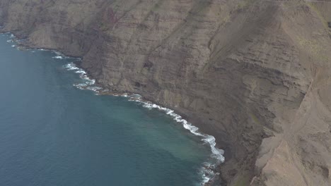 Panorama-drone-shot-of-waves-bounce-on-rocks-at-the-coast