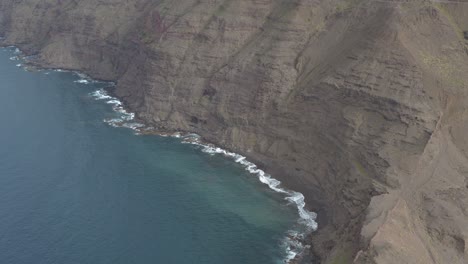 panorama drone shot of waves bounce on rocks at the coast