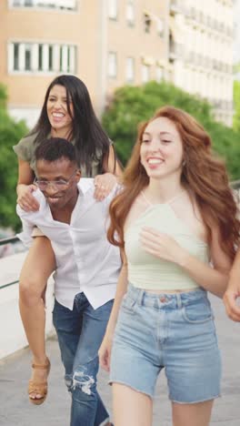 joyful friends having fun outdoors with a piggyback ride
