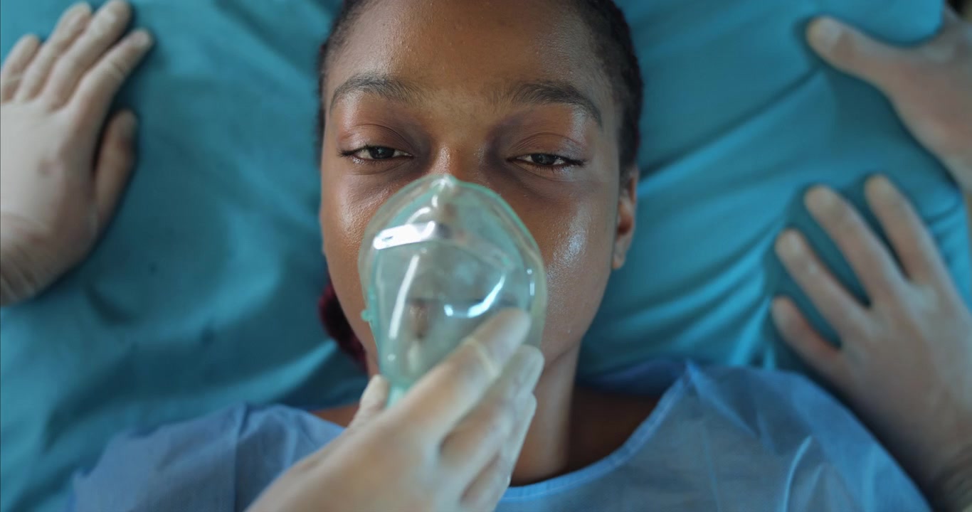 Primo piano di giovane donna afroamericana che riceve una maschera per l'ossigeno