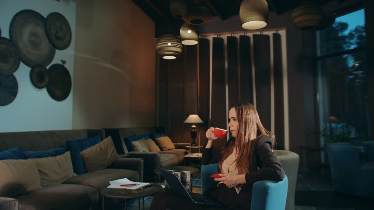 Forretningskvinde drikker kaffe i hotellounge. Forretningskvinde drikker te.