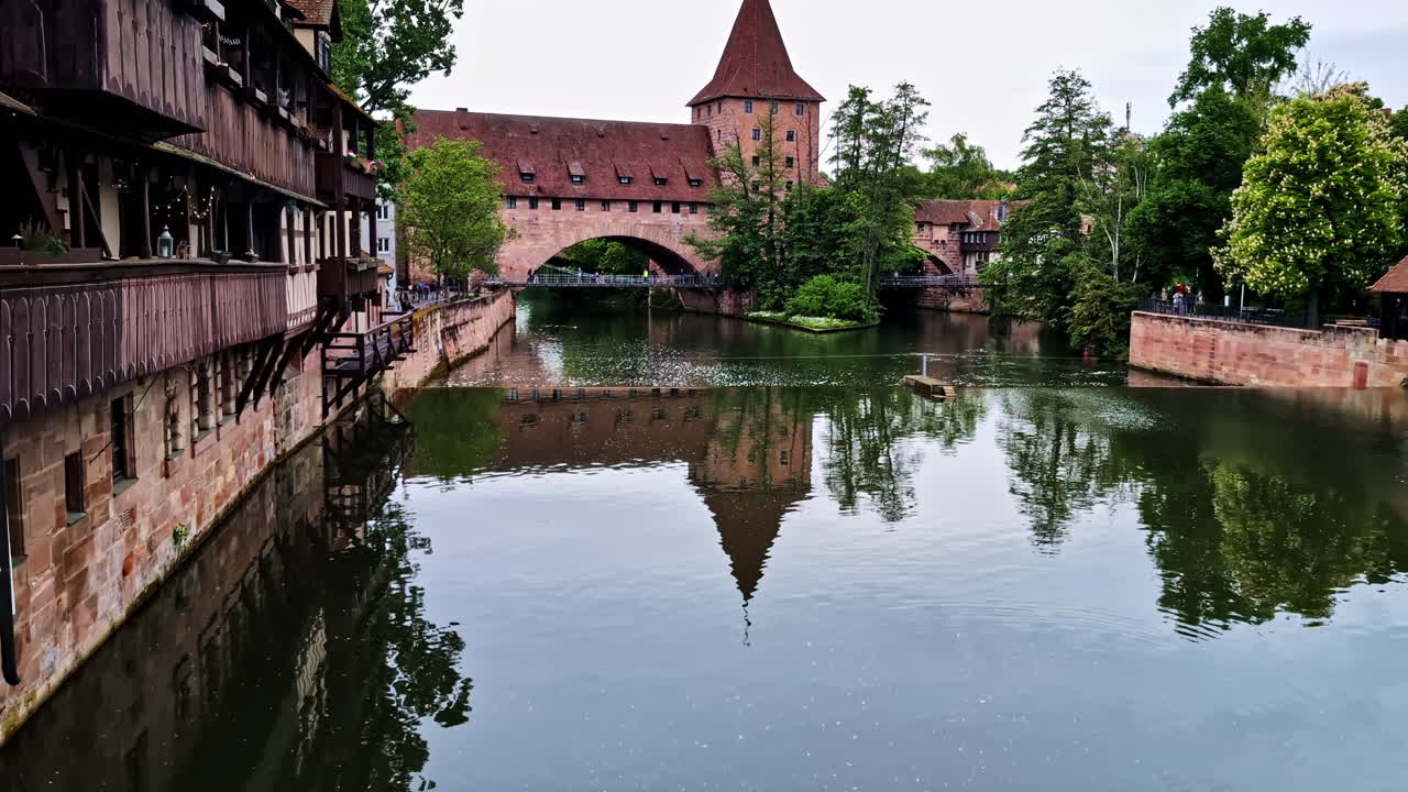 Fronveste tower and medieval buildings reflect in calm river water in Nurnberg