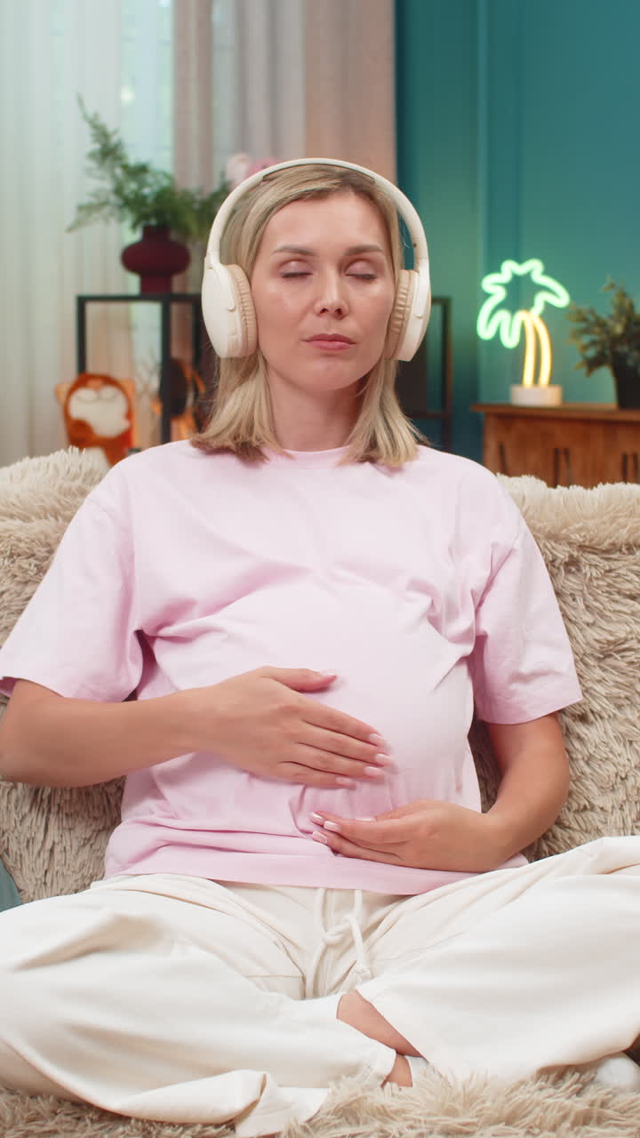 Pregnant woman meditating with headphones ocean sound stroking belly calm breathing focus deep peace