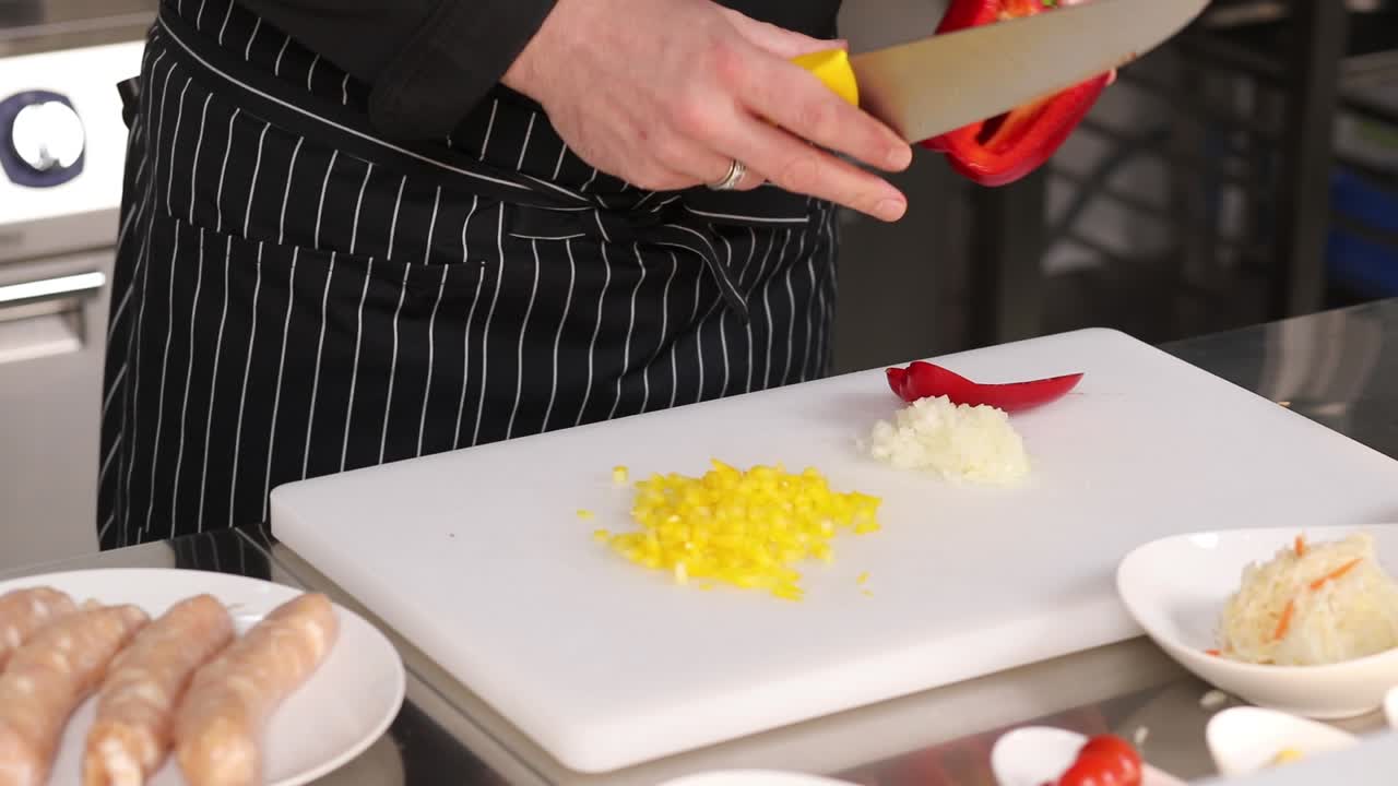 chef preparando una comida con pimientos, cebollas y salchichas