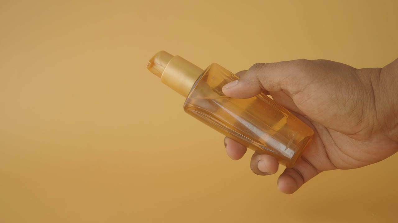 mano con una botella de bomba de ámbar de color dorado