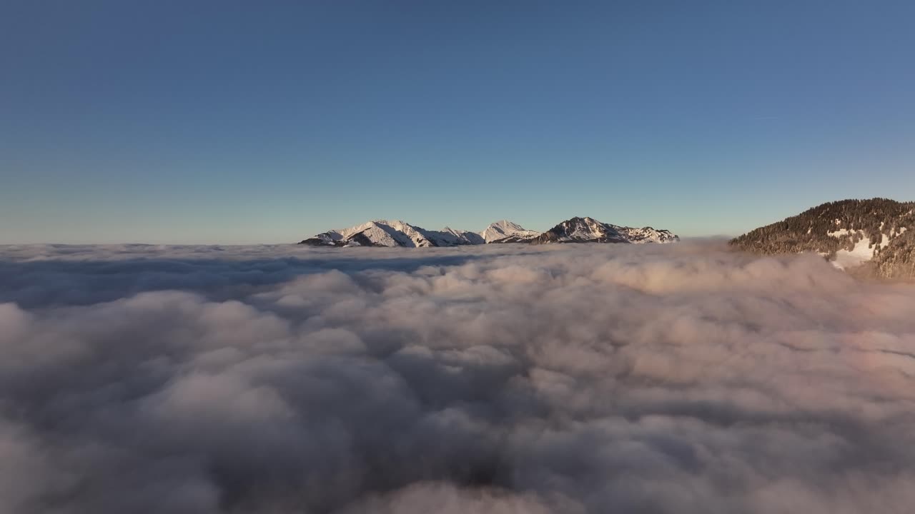 Serene aerial view of Rautispitz and Glärnisch peaks, rising above dense sea of clouds in distance, Glarus Nord, Switzerland.