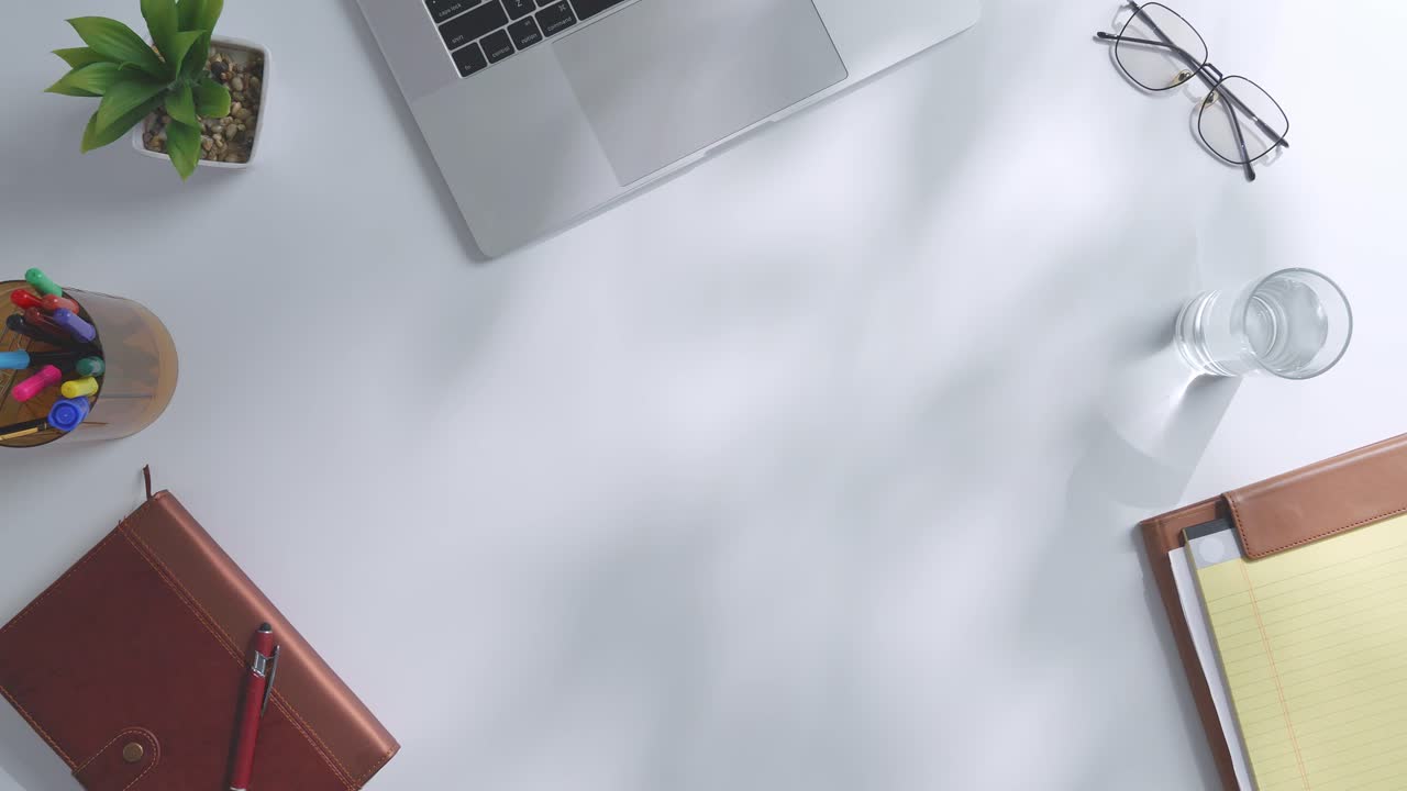 초록색 화면을 모방한 노트북 컴퓨터의 상단에서 아래로 볼 때, 펜, 안경, 그리고 물 한 잔을 가진 노트북 에 나무 사무실 책상 위에 크로마키 디스플레이가 있습니다.