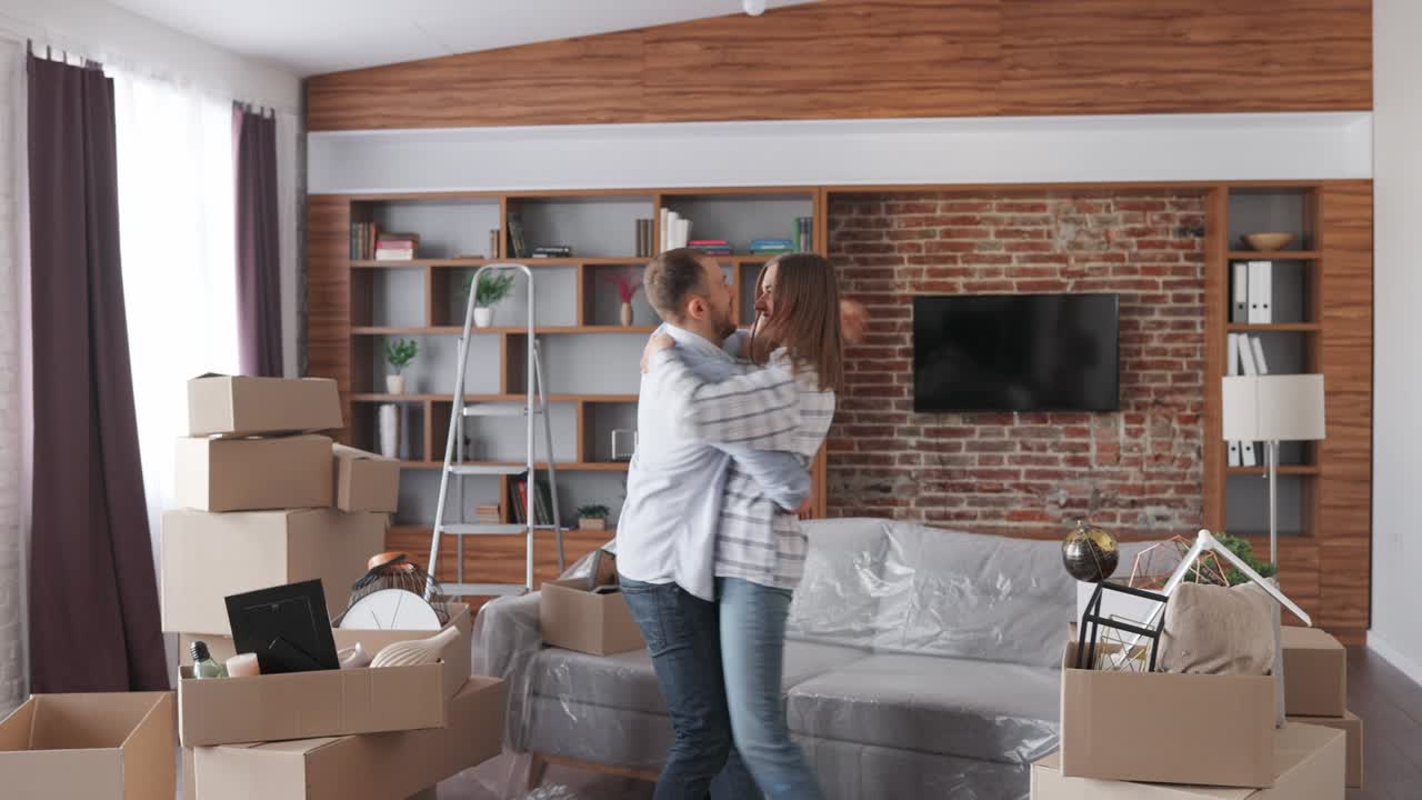 propietarios felices bailando y divirtiéndose en el día de la reubicación. pareja joven mudándose a un nuevo apartamento. nuevo alojamiento o apartamento alquilado. bienes raíces y concepto de alquiler. préstamo hipotecario para familia joven.