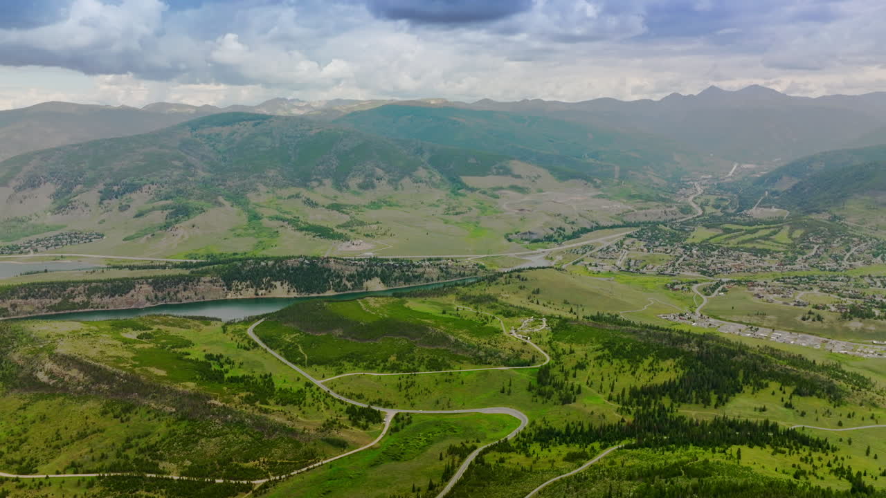 Amazingly beautiful green valleys near the rivers in mountainous region. Little town at the foot of mountain in Colorado. Dramatic sky over the mountain range at backdrop.