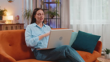 Angry stressed young caucasian woman talking laptop using computer webcam video call on sofa at home