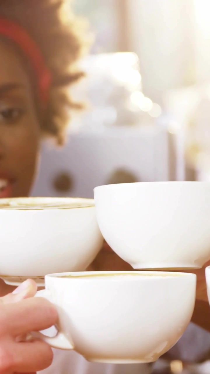 Vertical video: Pullback revealing barista balancing white cups, charts over cups for finance