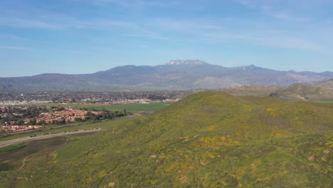 Drone-shot-flying-over-mountain-covered-in-wildflowers-during-the-California-Superbloom