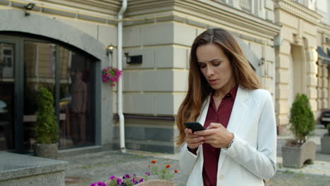 focused businesswoman typing message on mobile phone outdoors