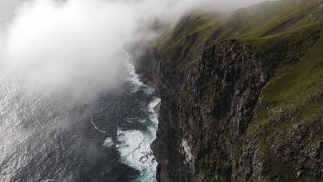 Drone-footage-of-very-high-cliffs-and-clouds-near-the-Witch-Finger-at-Sandavagur-on-the-Vagar-island-in-the-Faroe-Islands