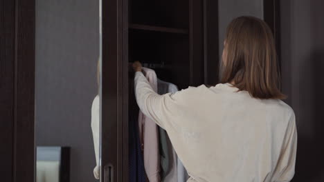 woman choosing clothes in front of a mirror