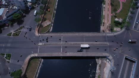 puente de tráfico y paso elevado en la ciudad de ho chi minh, vietnam, vista de seguimiento aéreo de arriba hacia abajo en un día soleado con el canal, los tejados y el tráfico rodado