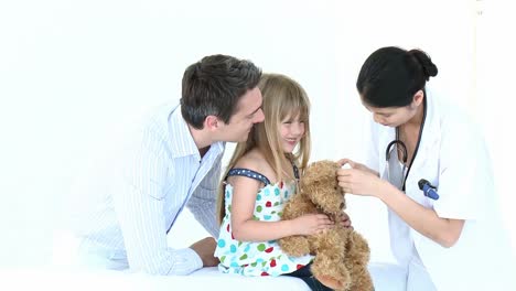 doctor jugando con una niña pequeña y su oso de peluche