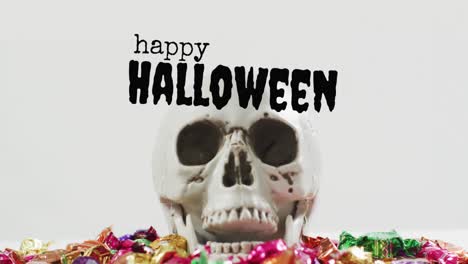 Animation-of-halloween-text-over-skull-with-sweets-on-grey-background