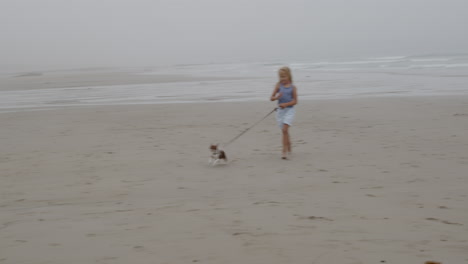 girl walking dog on a foggy beach