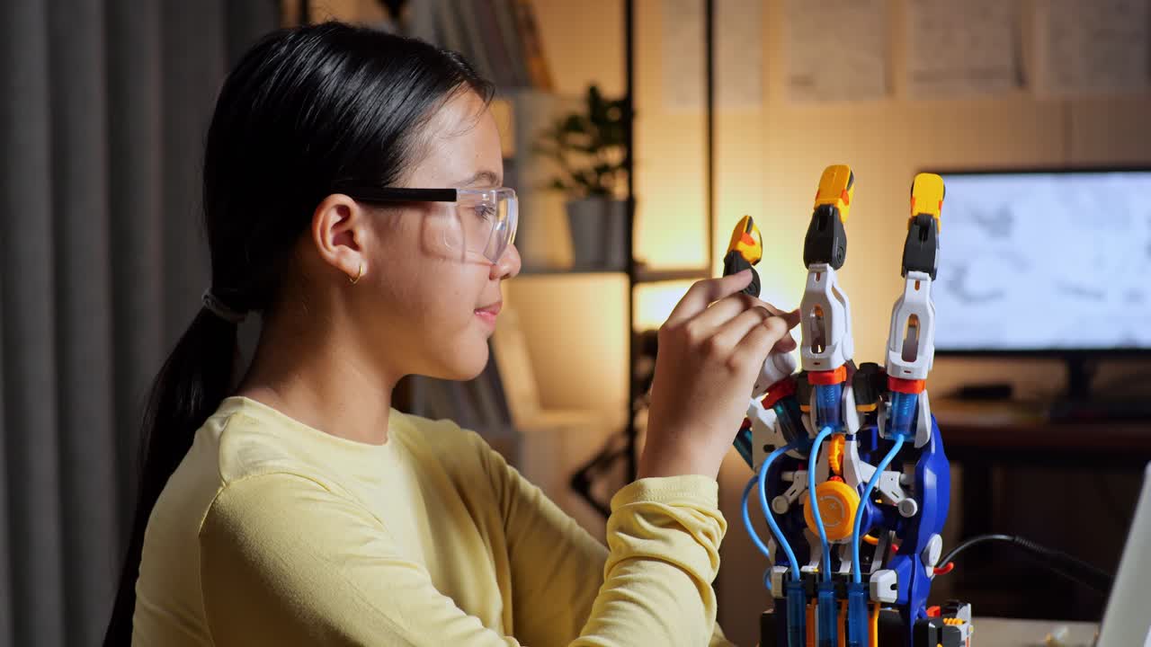 집에서 사이보그 손에 대해 작업하는 동안 노트북을 들고 미소 짓고 카메라로 팔을 는 십대 아시아 소녀의 클로즈업