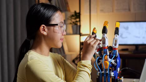 close up of teen asian girl with a laptop smiling and crossing her arms to the camera while working about a cyborg hand at home