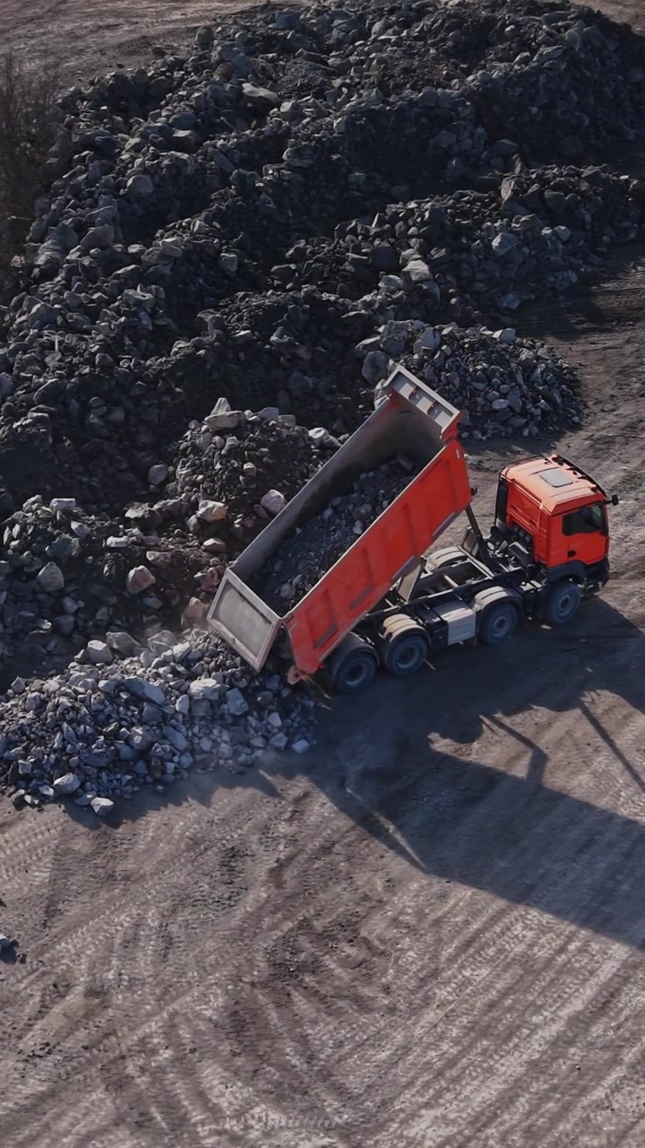 I camion scaricano pietre nel sito della cava durante le ore diurne