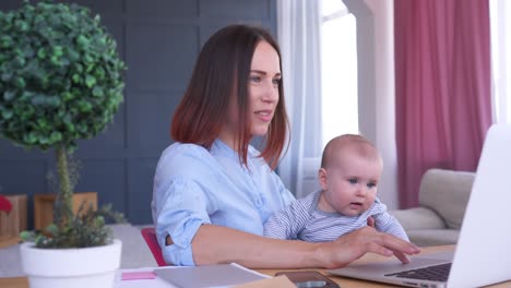 счастливая мать держит девочку, работая дома