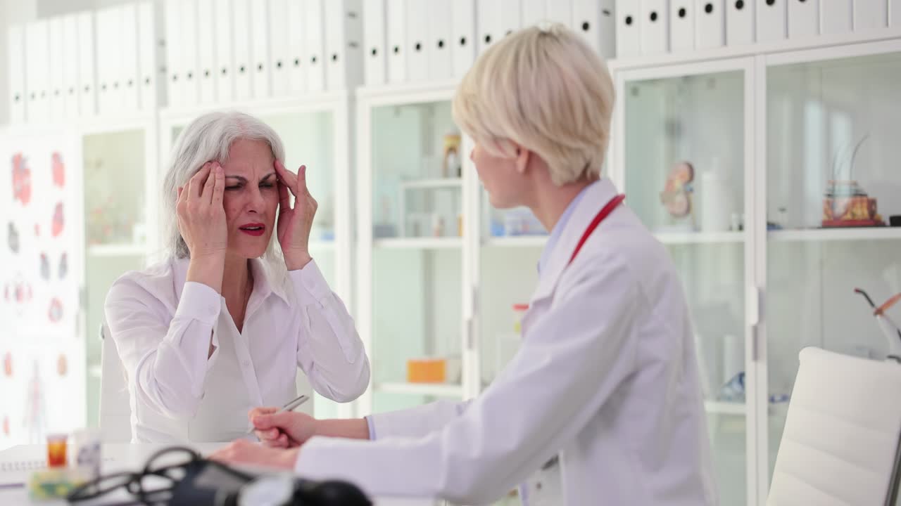 Senior woman consulting with doctor about headache
