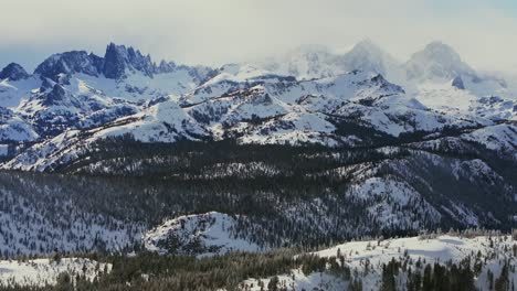 the minarets jagged peaks mountain range summit vista mammoth mountain ski resort california winter spring deep snow hemlocks ritter sierra nevadas sunny blue sky clouds snowy deep snow backwards pan