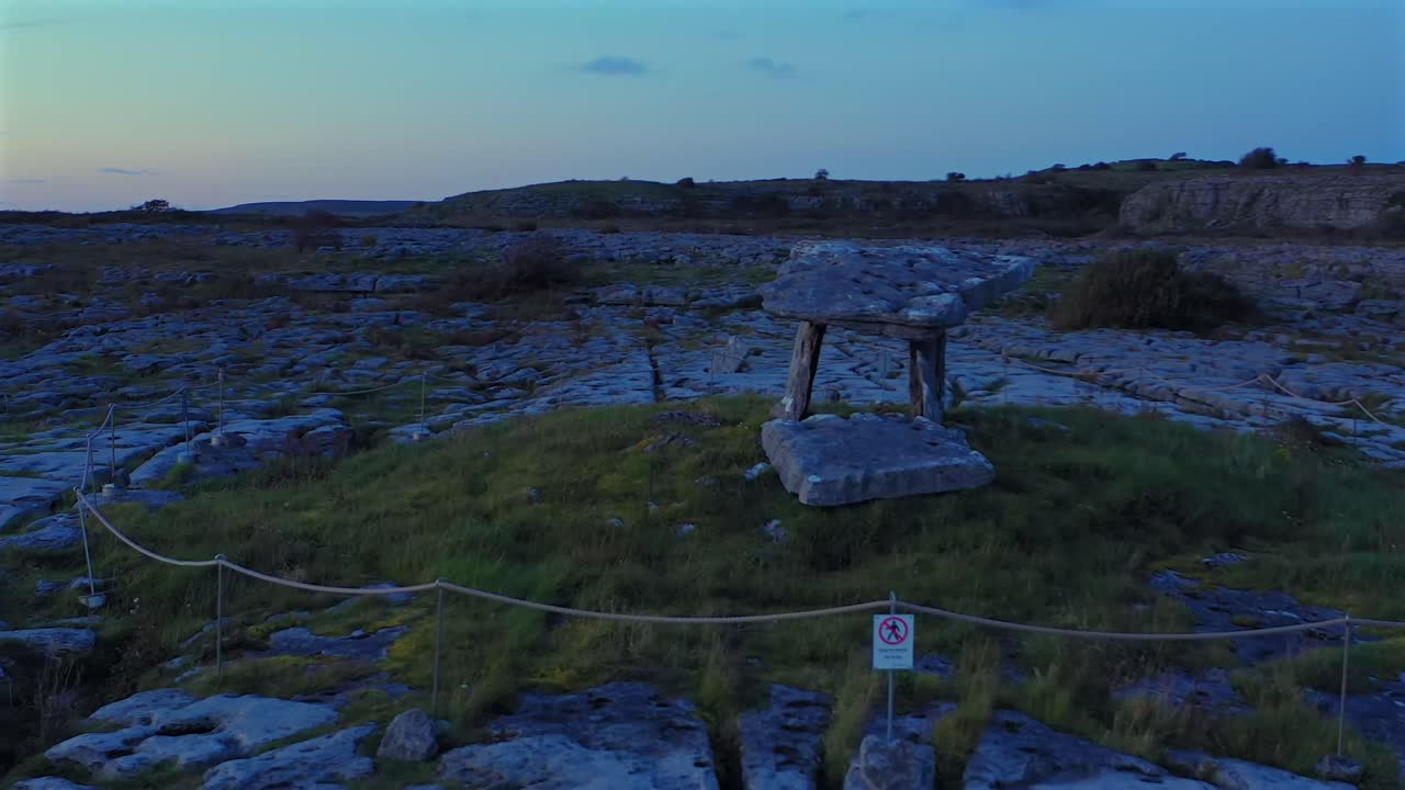 Lavtflygende luftopptak mot det eldgamle gravstedet Poulnabrone Dolmen i Burren nasjonalpark i skumringen