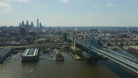 Antenne---Statische-Ansicht,-Während-Fahrzeuge-Ben-Franklin-Bridge-Mit-Philadelphia,-Pennsylvania-Im-Hintergrund-überqueren