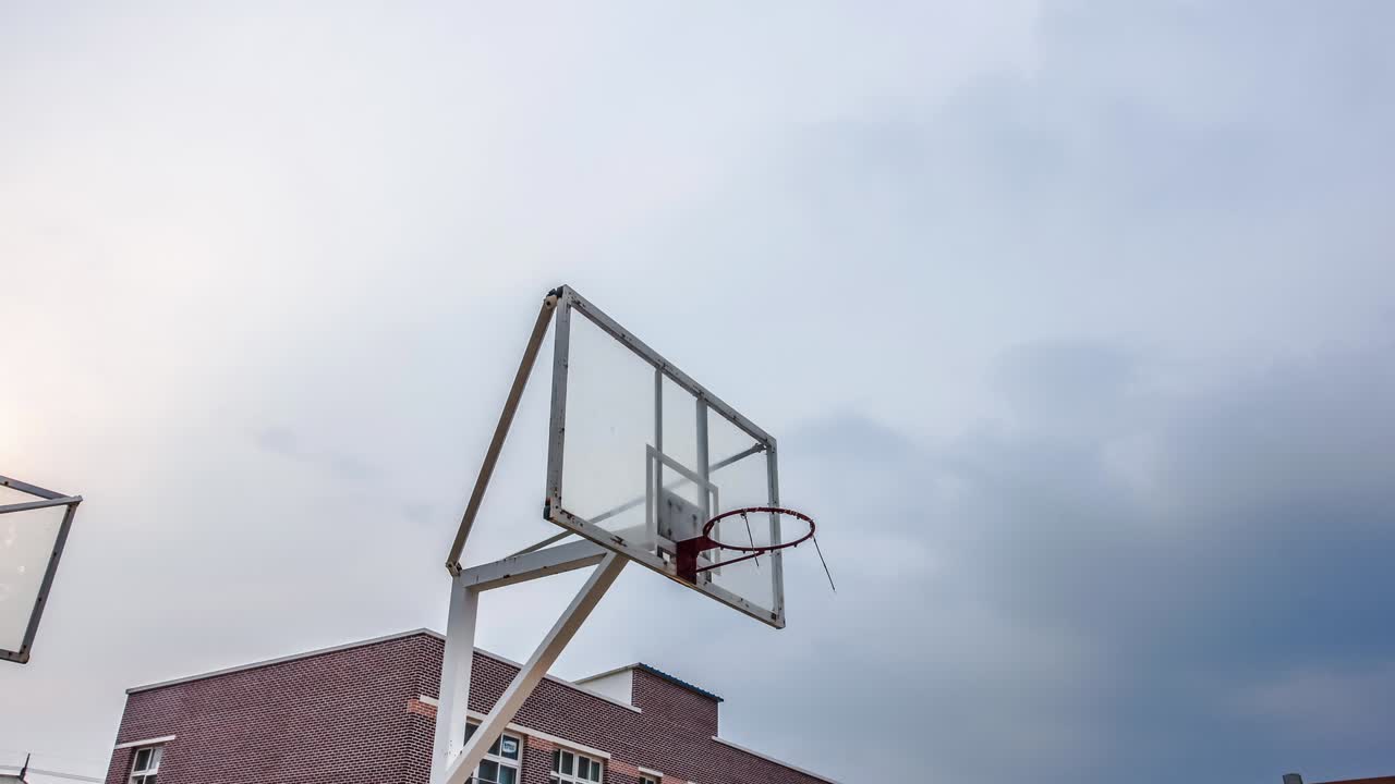 un ring de baloncesto en una escuela en asia con fondo nublado de lapso de tiempo