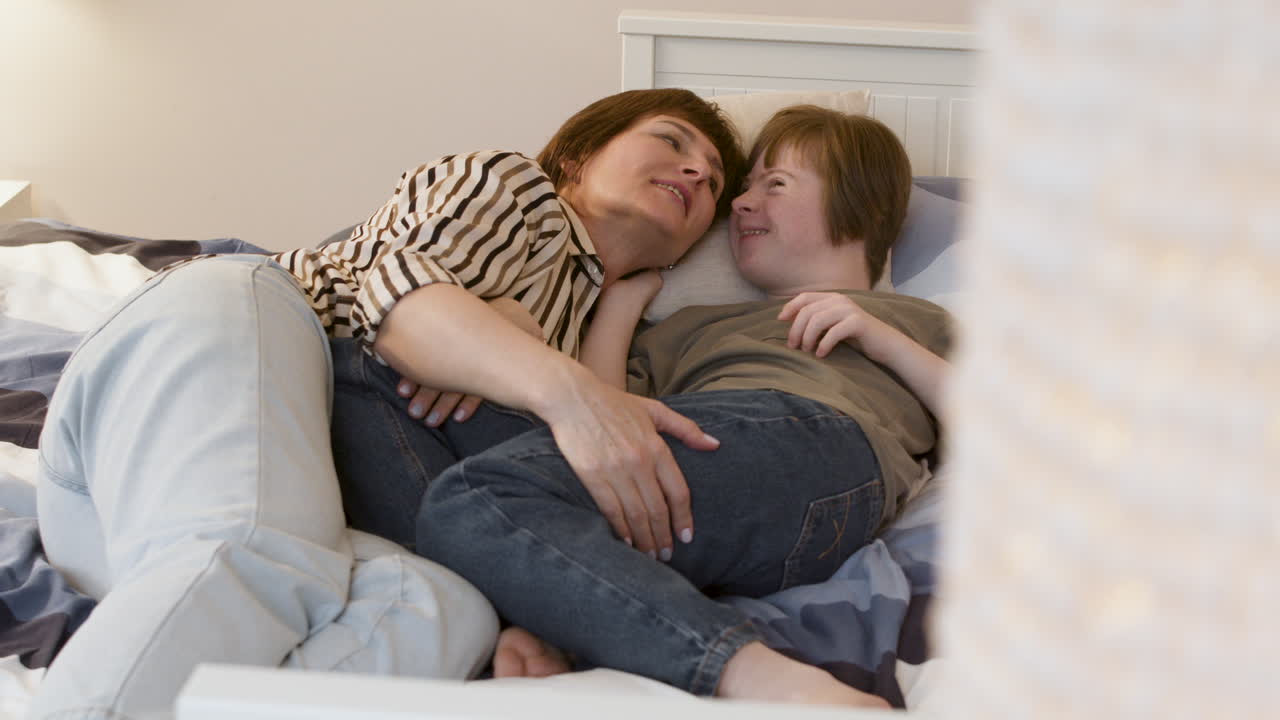 어머니와 딸이 침대에서 이야기하고 웃고 있습니다.