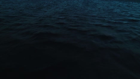 Deep-blue-dusk-ocean-wave-texture,-dark-aerial-drone-dolly-push-in