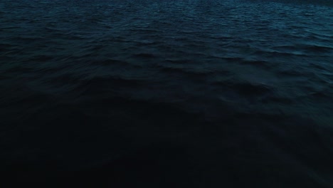 deep blue dusk ocean wave texture, dark aerial drone dolly push in