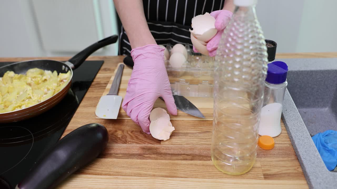 Person cracking eggs for cooking in a kitchen