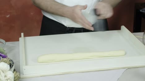 chef skillfully rolls and spreads dough out then divides it using dough cutter