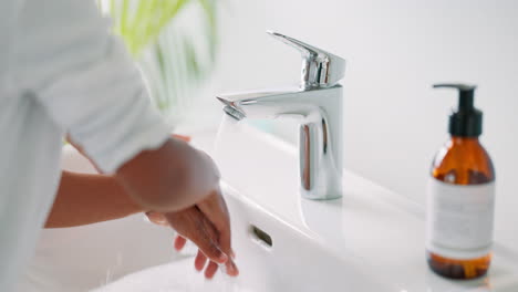 el lavabo, primer plano y la niña lavándose las manos