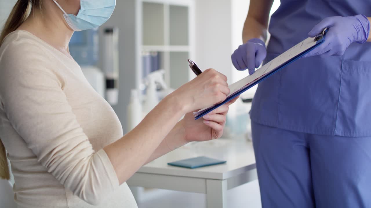 video de una mujer embarazada firmando documentos antes de la vacunación