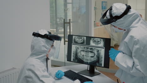 dentistry staff looking at dental x ray scan wearing ppe suits