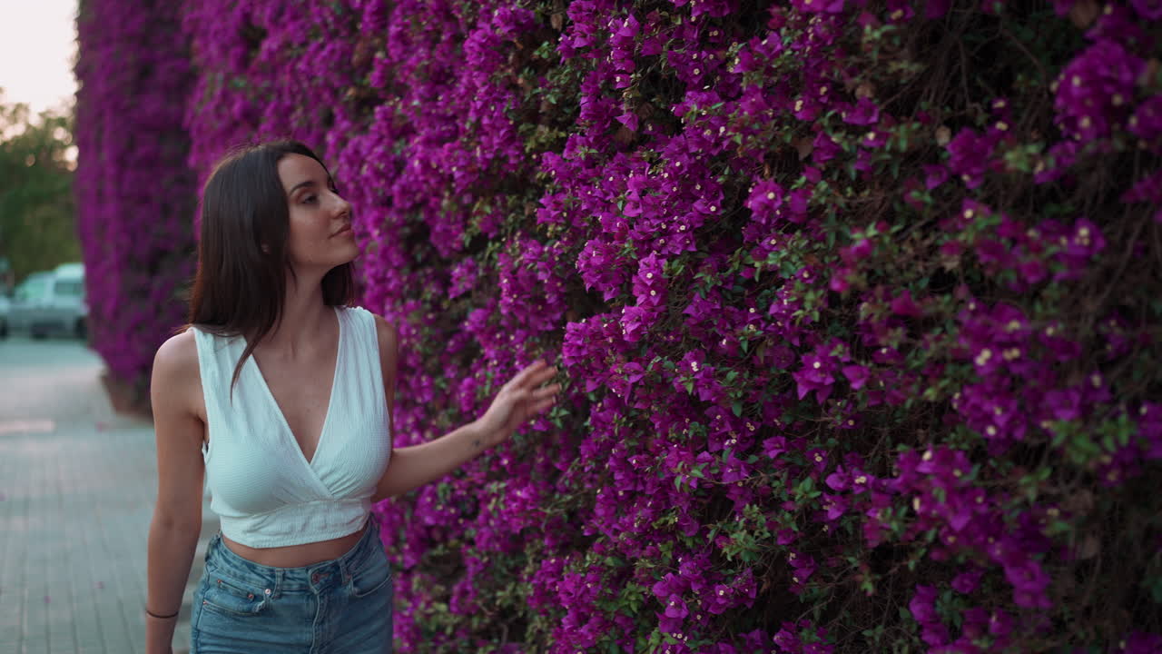 Woman standing next to a wall of purple flowers
