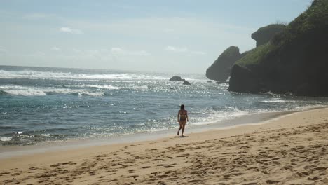 Slow-motion-shot-of-a-girl-walking-down-the-beach-in-a-bikini-in-Uluwatu,-Bali