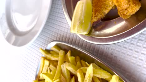 Vertical-Close-up-of-Golden-Fried-Seafood-with-Lemon-and-Fried-Chips-in-Lisbon,-Portugal