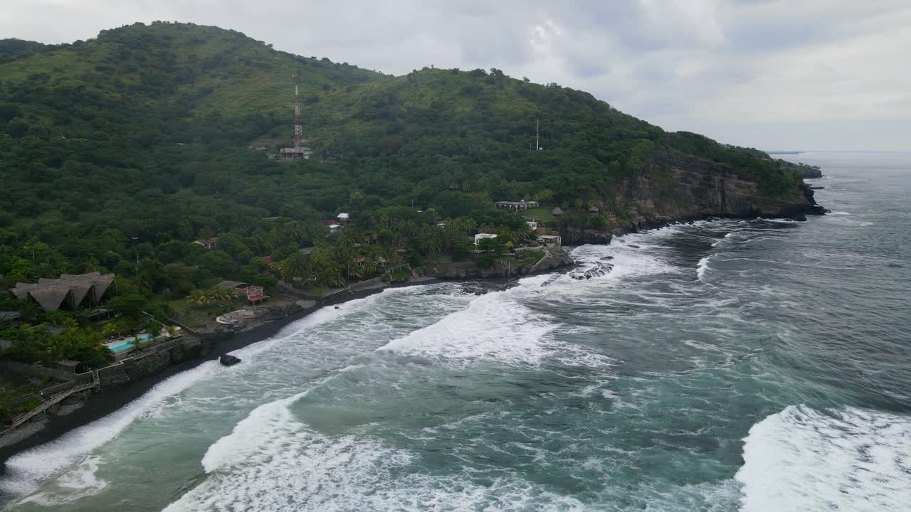 Aerial view moving away shot, scenic view of waves rushing to the shore of the bitcoin beach in El Salvador Mexico, blue sky in the background
