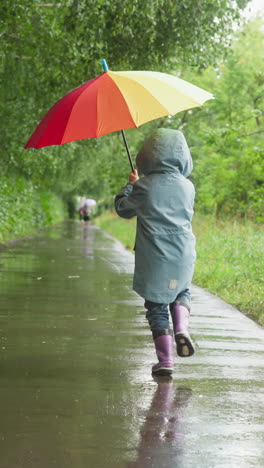 kid runs in park with colorful umbrella. child carefree spirit shines brightly among gray surroundings. joy and freedom in dreary rainy day