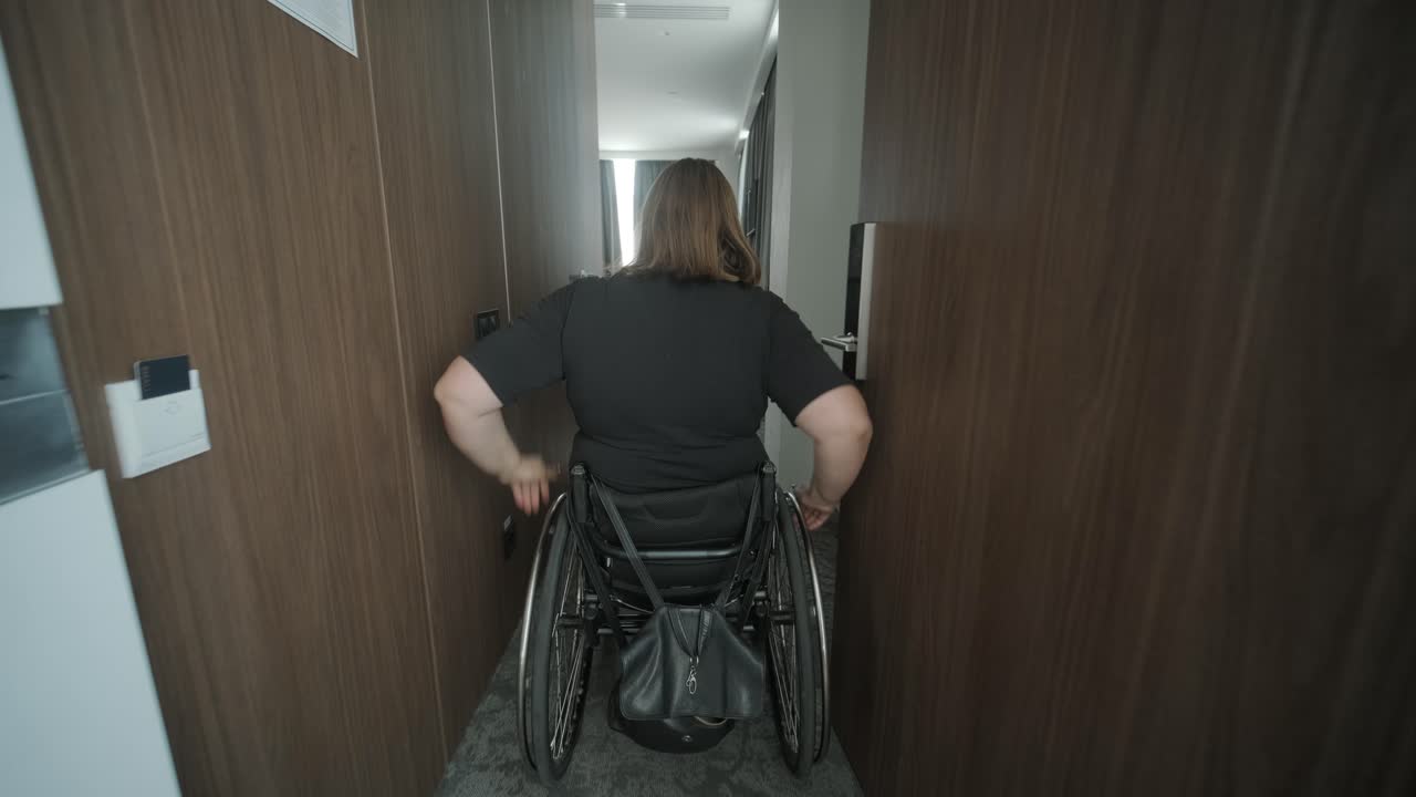una mujer en silla de ruedas navega a través de una habitación de hotel, destacando alojamientos accesibles y diseño inclusivo. la imagen hace hincapié en la movilidad, la independencia y la infraestructura de hospitalidad moderna.